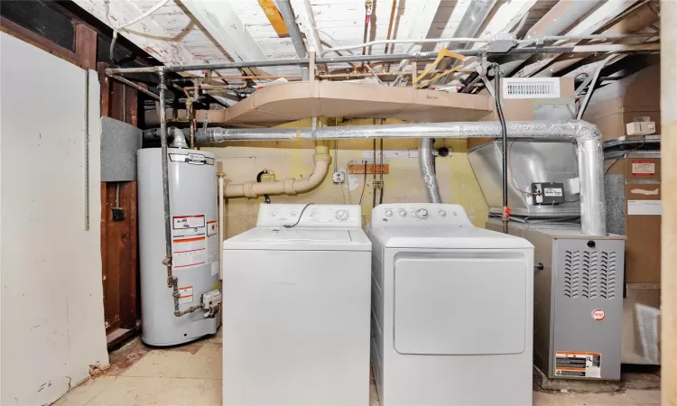 Washroom with water heater, laundry area, visible vents, and separate washer and dryer