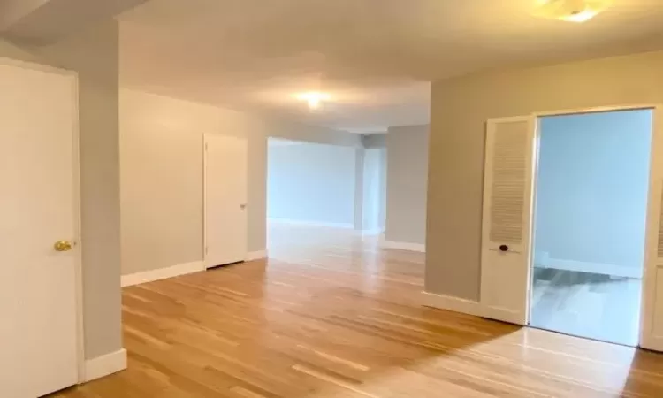 Spare room featuring light wood-style flooring and baseboards