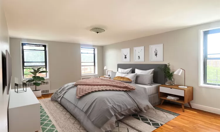 Bedroom featuring light wood-style floors, multiple windows, radiator, and baseboards