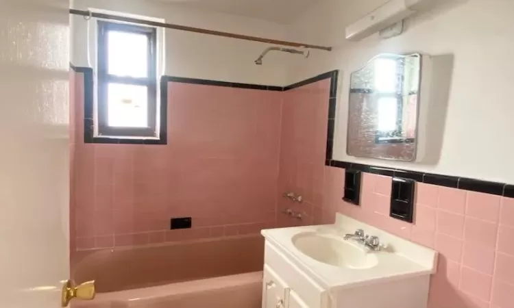 Full bath featuring vanity, tile walls, and tub / shower combination