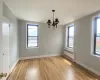 Unfurnished dining area featuring an inviting chandelier, radiator, light wood-style floors, and baseboards