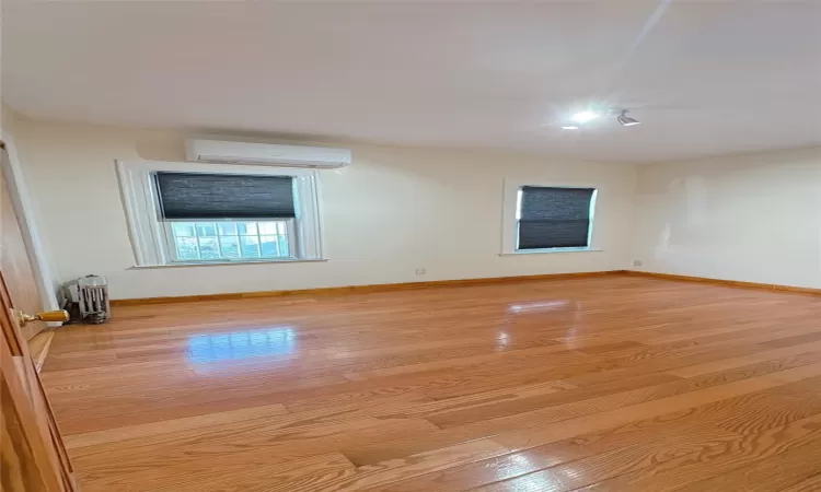 Spare room with light wood-type flooring, baseboards, and a wall mounted AC