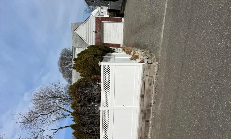 View of side of home featuring brick siding and fence