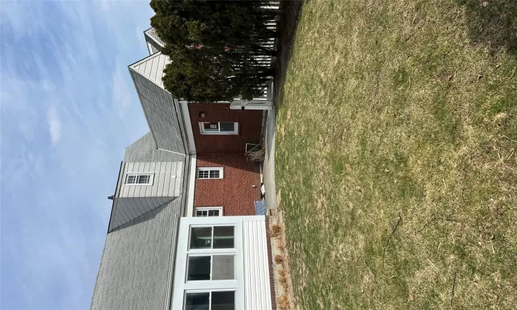 Rear view of house featuring a yard, a patio area, and brick siding