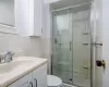 Bathroom featuring vanity, toilet, tile walls, and a shower stall