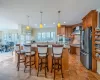 Kitchen featuring a sink, appliances with stainless steel finishes, a kitchen bar, tile patterned floors, and wall chimney range hood