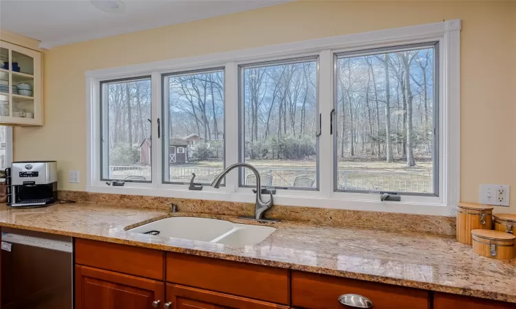 Kitchen featuring glass insert cabinets, a fireplace, freestanding refrigerator, wall chimney exhaust hood, and a sink