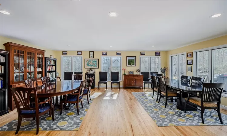 Dining space featuring baseboards, recessed lighting, crown molding, a brick fireplace, and light wood-type flooring