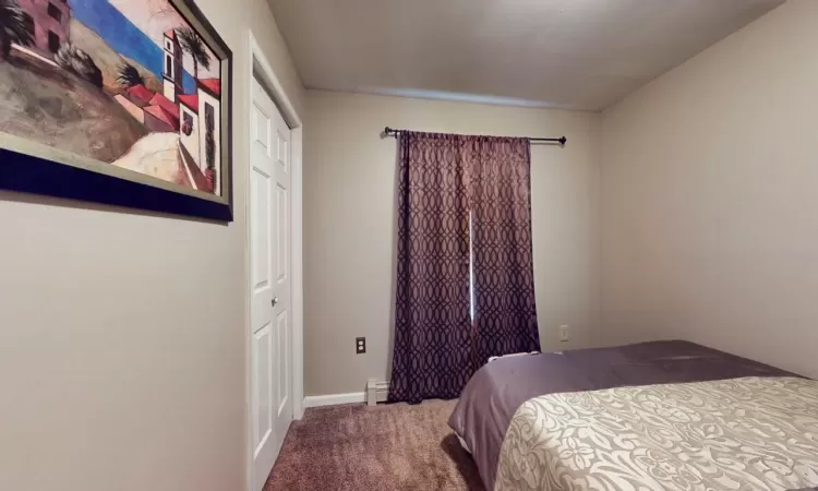 Bedroom with a baseboard heating unit, carpet, and baseboards