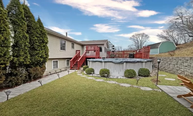 Rear view of house with a wooden deck, a yard, a fenced in pool, and fence