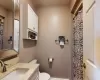 Bathroom with curtained shower, a baseboard heating unit, toilet, and vanity