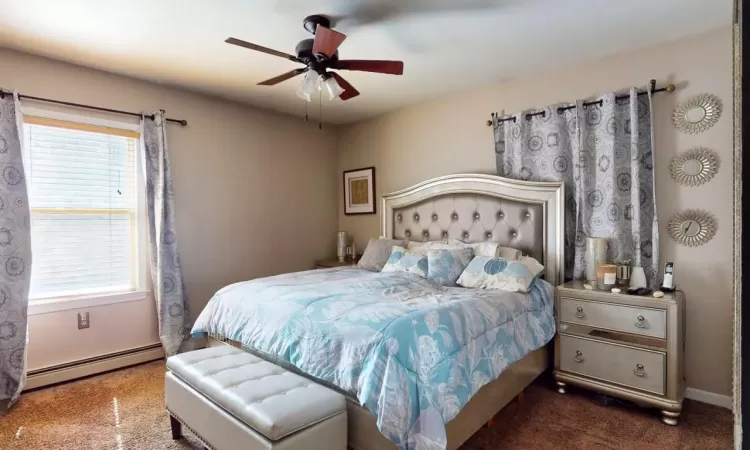 Bedroom featuring a ceiling fan, a baseboard heating unit, and baseboards