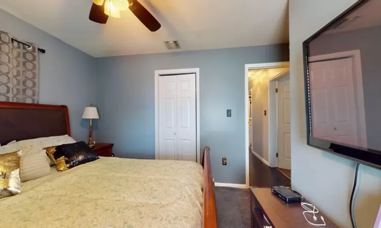 Bedroom with visible vents, dark carpet, a closet, baseboards, and ceiling fan