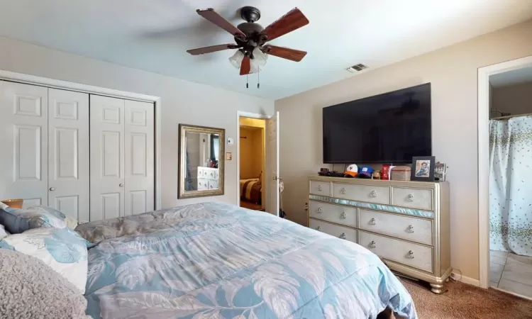 Carpeted bedroom featuring a closet, visible vents, baseboards, and ceiling fan