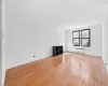 Unfurnished living room with radiator heating unit, baseboards, and light wood-type flooring