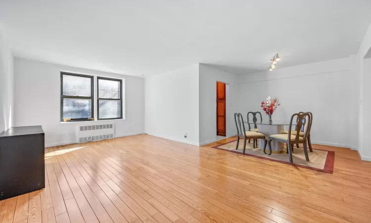 Dining space featuring radiator heating unit, baseboards, and light wood finished floors