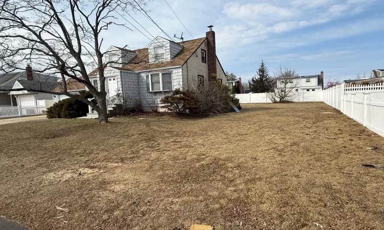 View of side of home featuring a lawn, fence private yard, and a chimney