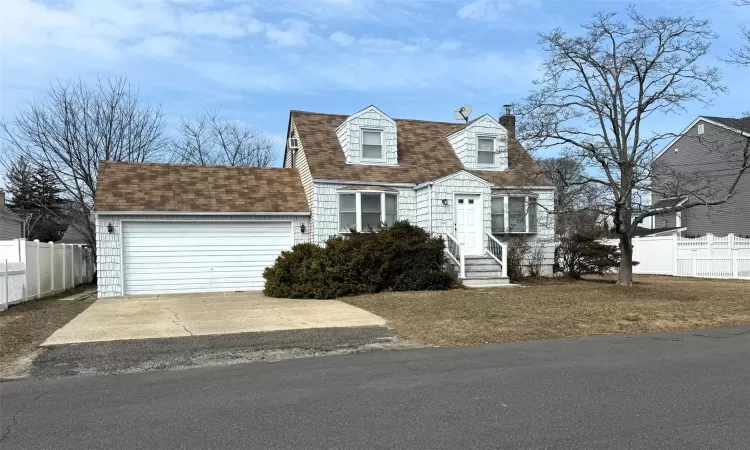 View of front of property featuring a shingled roof, fence, a chimney, a garage, and driveway