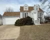 Cape cod home with concrete driveway, an attached garage, and a shingled roof