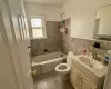 Bathroom featuring vanity, a wainscoted wall, bathing tub / shower combination, tile walls, and toilet