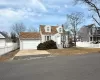 View of front of home featuring a shingled roof, fence, entry steps, a chimney, and a garage