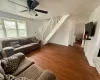 Living room with stairway, ceiling fan, baseboards, and wood finished floors