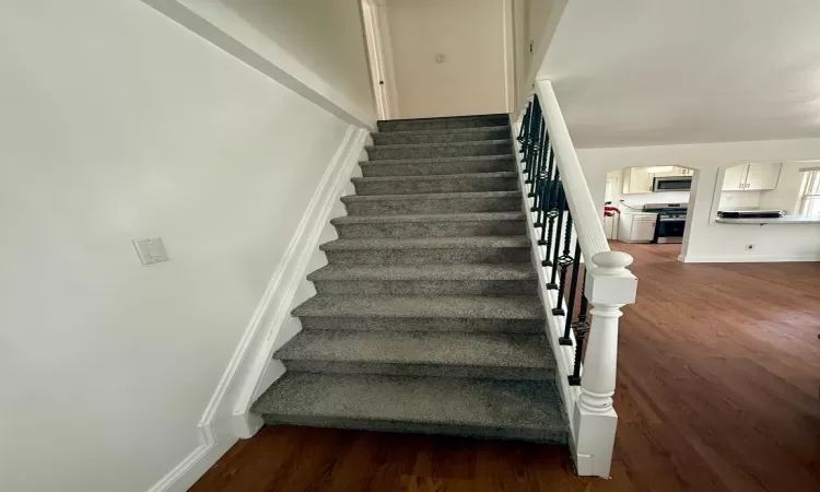 Staircase featuring baseboards, arched walkways, and wood finished floors