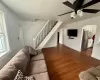 Living area with a ceiling fan, stairway, dark wood-style floors, and baseboards