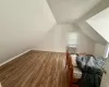 Bonus room featuring vaulted ceiling, radiator heating unit, baseboards, and wood finished floors