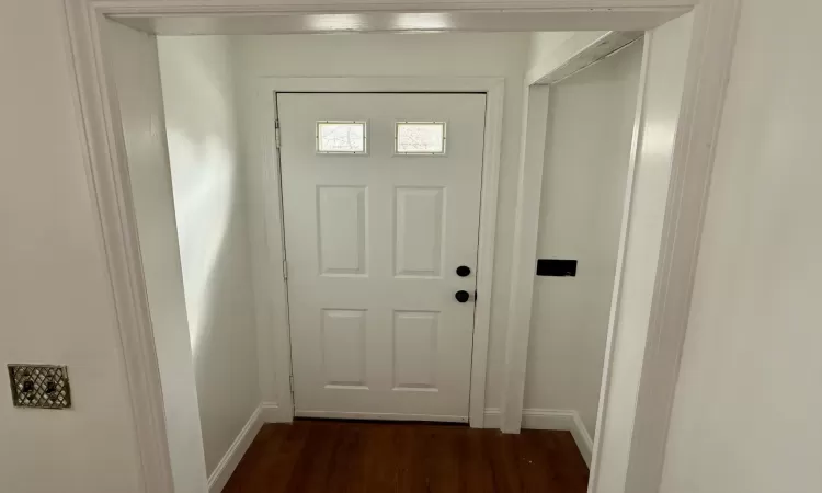 Doorway featuring baseboards and dark wood-style flooring