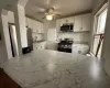 Kitchen featuring a ceiling fan, a sink, appliances with stainless steel finishes, white cabinets, and light countertops