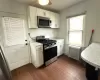 Kitchen featuring dark wood-type flooring, stainless steel appliances, radiator, white cabinets, and light countertops