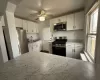 Kitchen with arched walkways, ceiling fan, a sink, appliances with stainless steel finishes, and white cabinetry