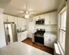 Kitchen featuring dark wood-style flooring, a sink, stainless steel appliances, light countertops, and white cabinets