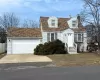 Cape cod-style house featuring a garage, concrete driveway, a chimney, and a shingled roof