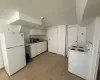 Kitchen with light countertops, light tile patterned floors, white cabinets, white appliances, and washer / clothes dryer