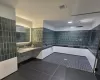 Bathroom featuring tile walls, tile patterned floors, visible vents, a sink, and walk in shower