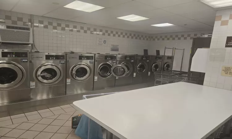 Community laundry room featuring tile patterned floors, separate washer and dryer, tile walls, and a wall mounted AC