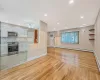 Unfurnished living room featuring recessed lighting, light wood-type flooring, baseboards, and a baseboard radiator