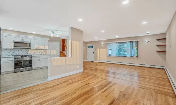 Unfurnished living room featuring recessed lighting, light wood-type flooring, baseboards, and a baseboard radiator