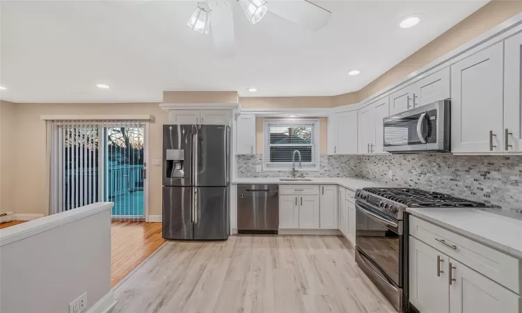 Kitchen with a sink, stainless steel appliances, light wood-style flooring, and light countertops