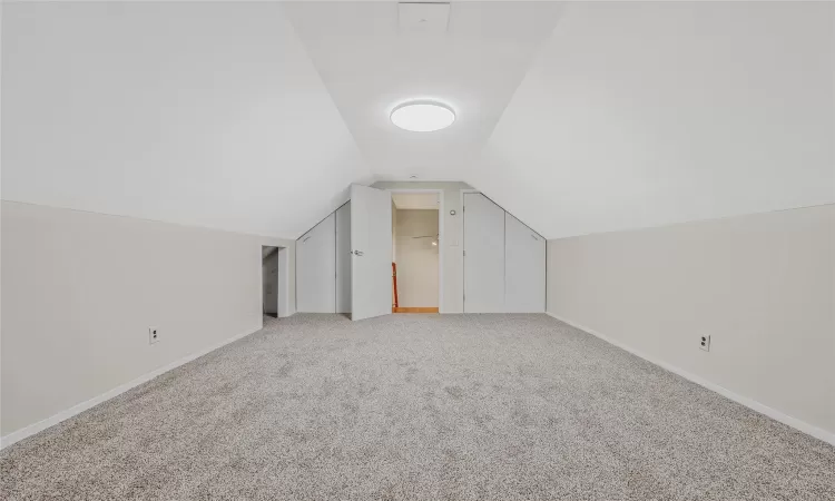 Bonus room featuring baseboards, light colored carpet, and vaulted ceiling