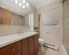 Full bath with tile patterned floors, toilet, tile walls, crown molding, and a baseboard radiator