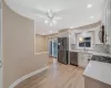 Kitchen with light wood-style flooring, a sink, backsplash, appliances with stainless steel finishes, and baseboards