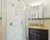 Bathroom featuring a stall shower, vanity, and tile walls