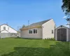 Rear view of property featuring an outbuilding, a lawn, a storage unit, and fence