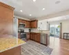 Kitchen with decorative backsplash, a peninsula, brown cabinetry, stainless steel appliances, and a sink