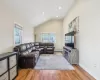 Living area featuring light wood-style flooring, baseboards, lofted ceiling, and a baseboard radiator