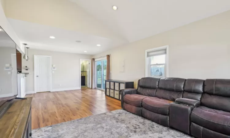 Living room with vaulted ceiling, recessed lighting, wood finished floors, and baseboards