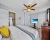 Bedroom featuring wood finished floors, baseboards, ensuite bathroom, and ceiling fan